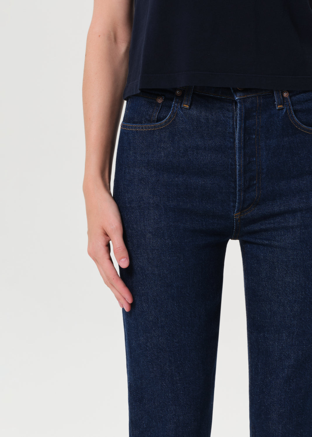 Person wearing dark blue jeans on a light gray background