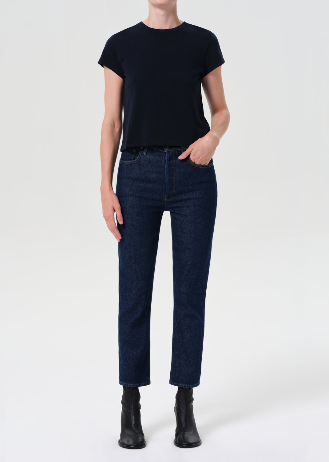 Person wearing a black t-shirt and dark blue jeans on a white background