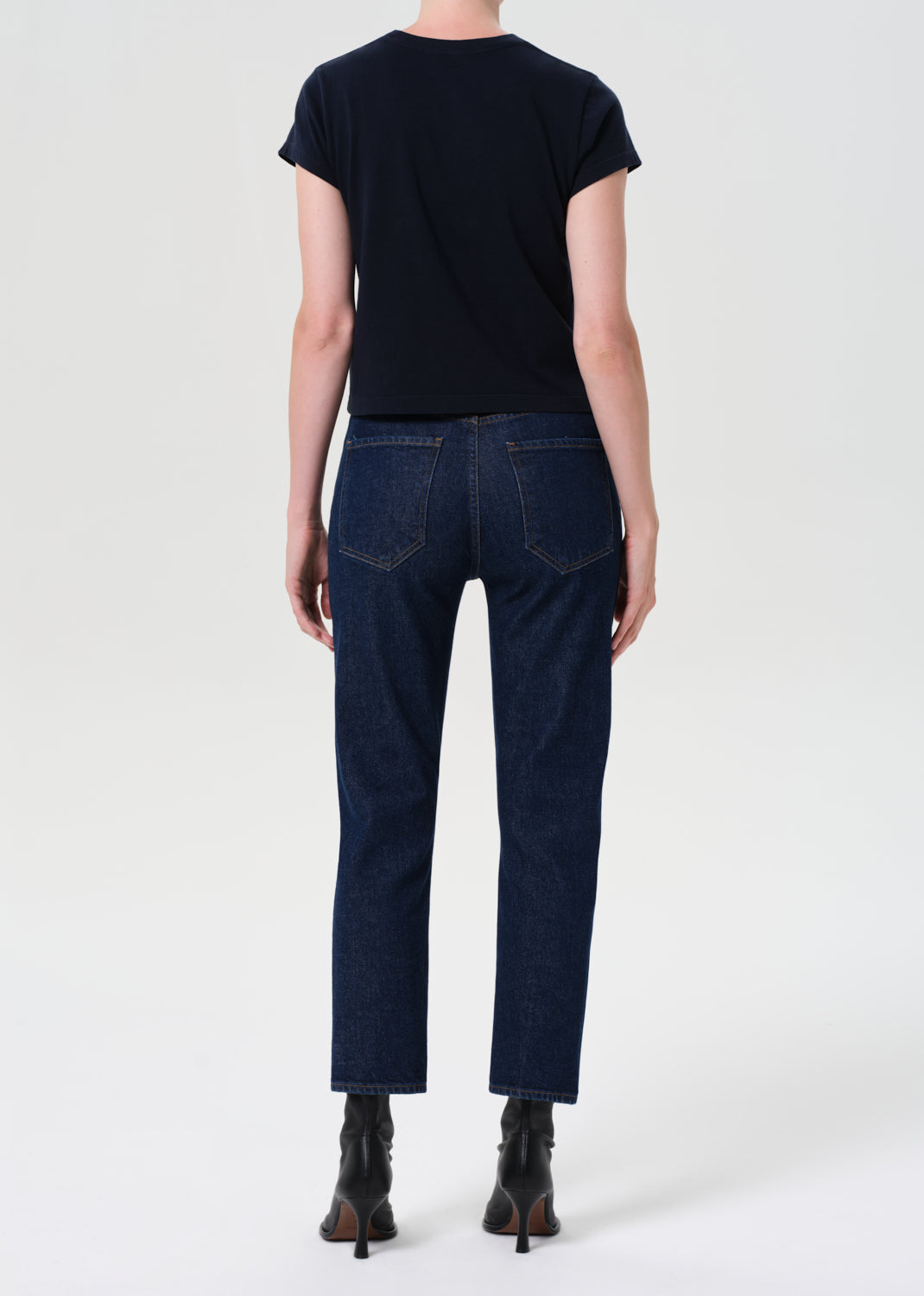 Person wearing a black t-shirt and dark blue jeans on a white background