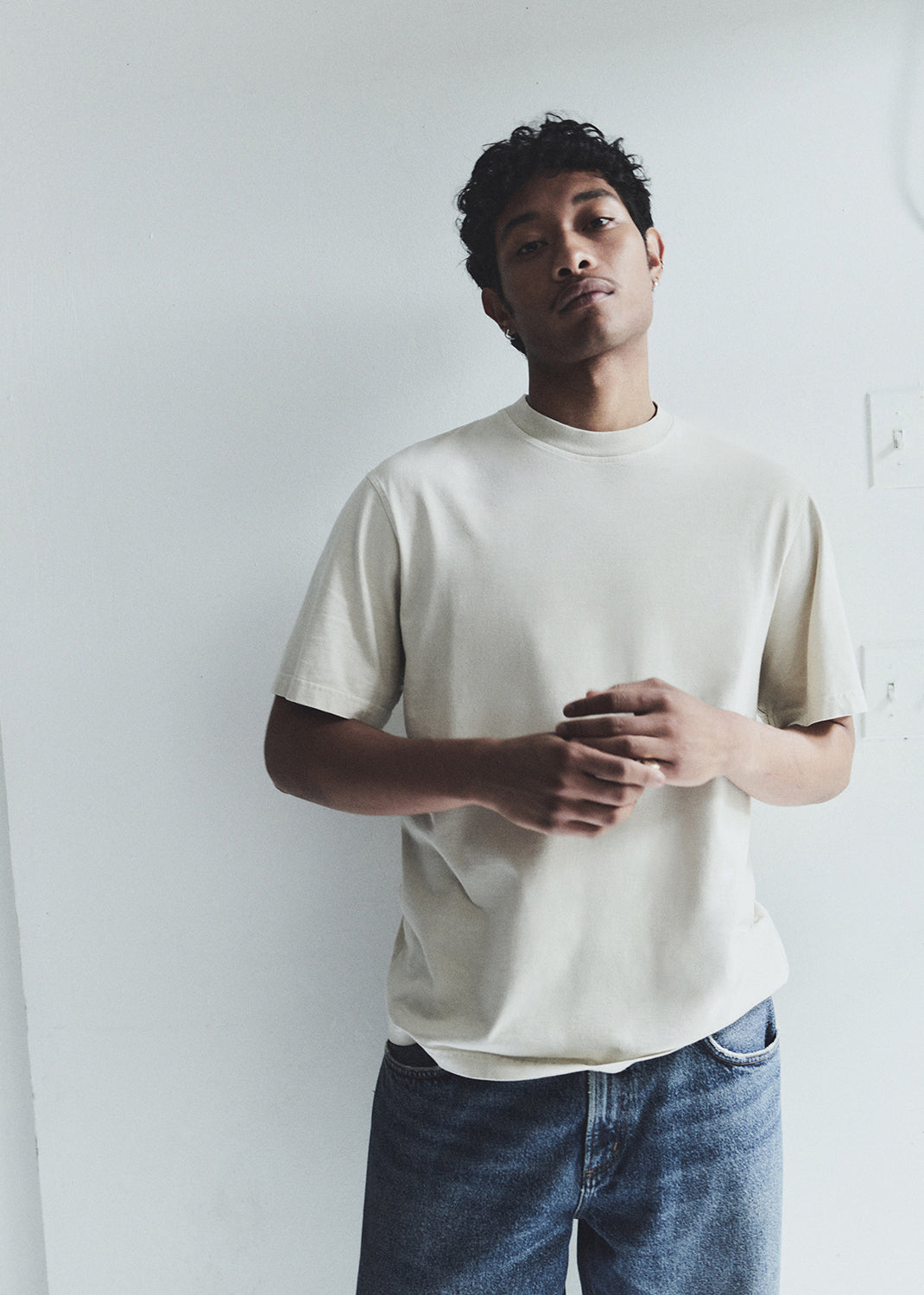 Man wearing a plain white t-shirt and blue jeans against a white background