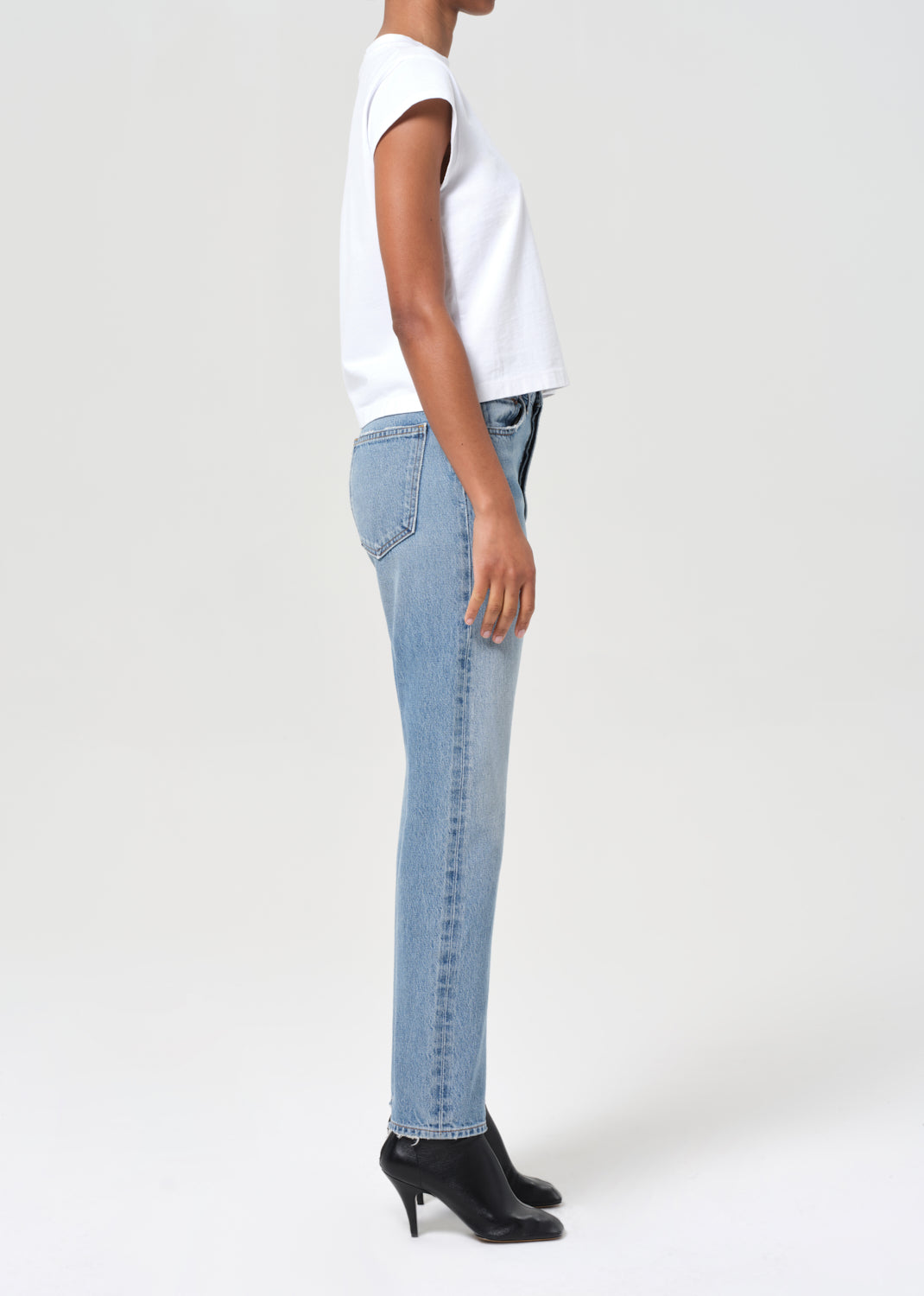 Person wearing light blue jeans and a white top on a white background