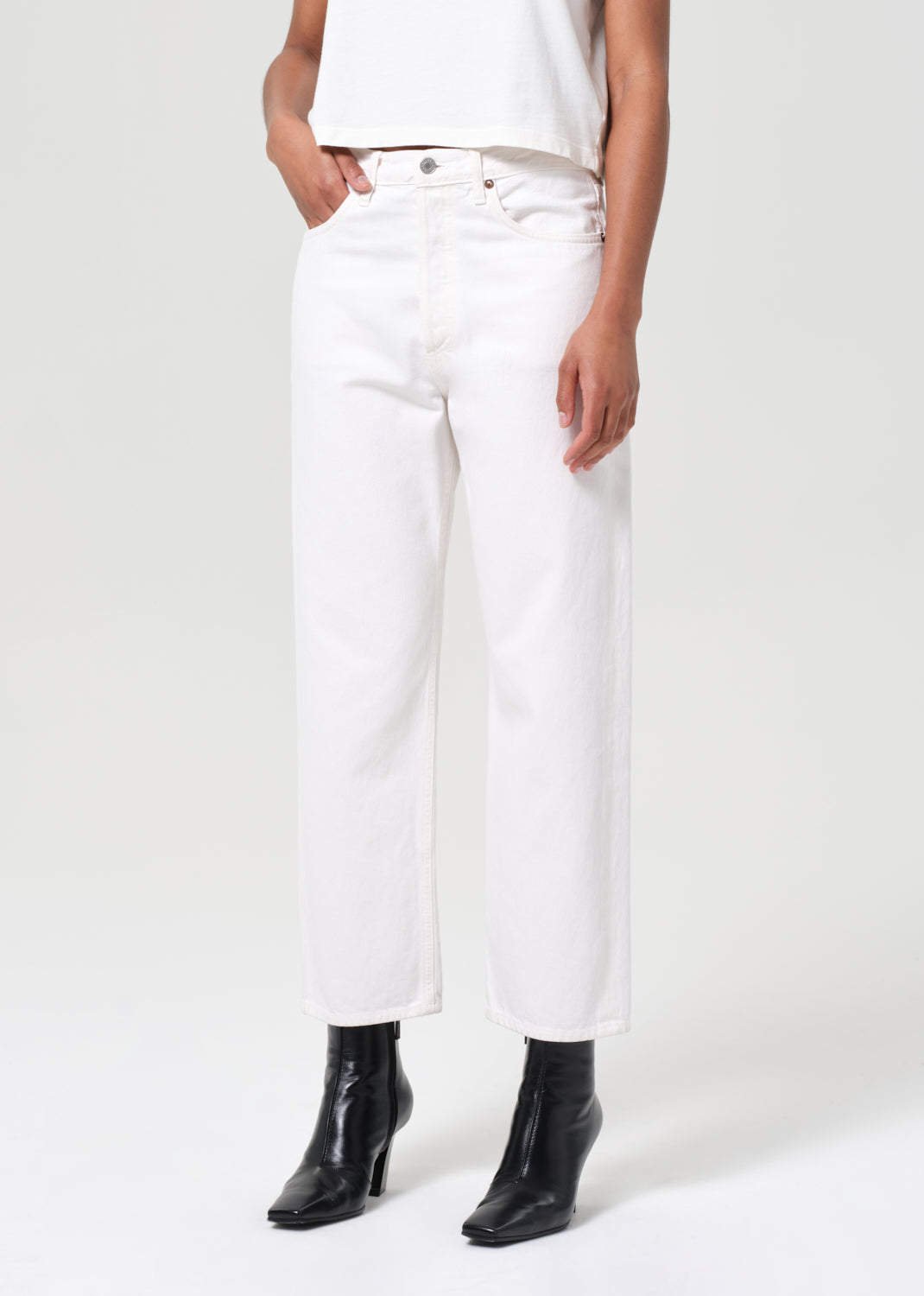 Person wearing white pants and black boots on a white background
