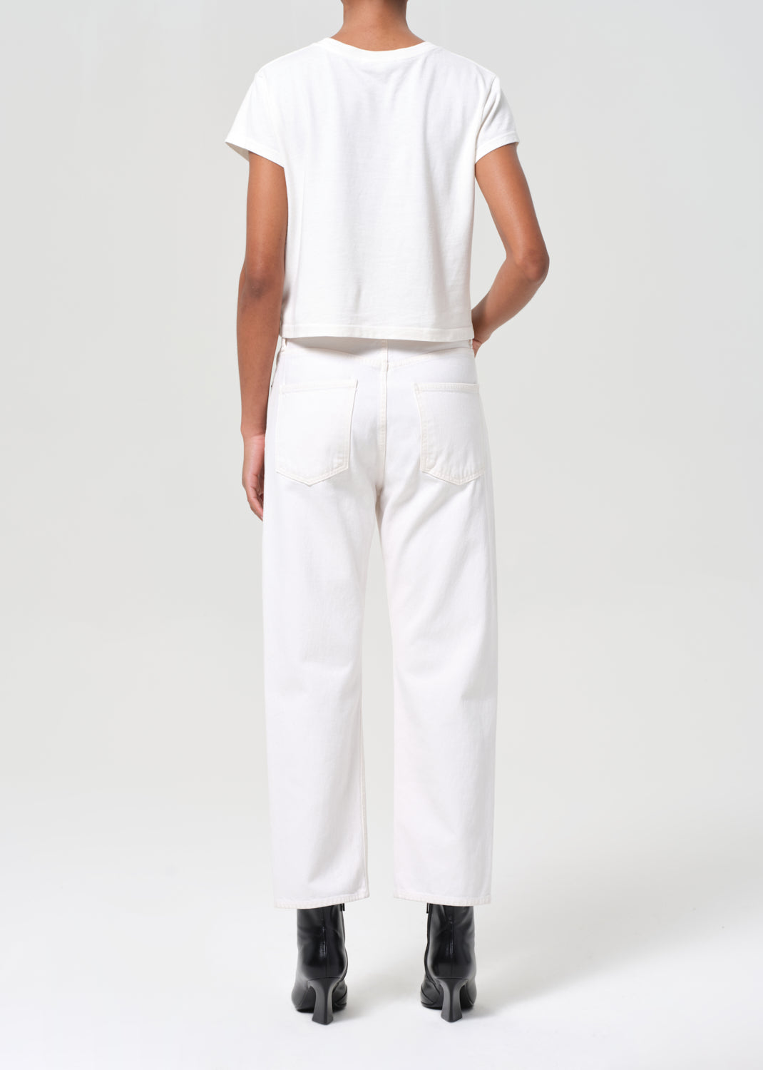 Person wearing a white outfit with black shoes on a white background