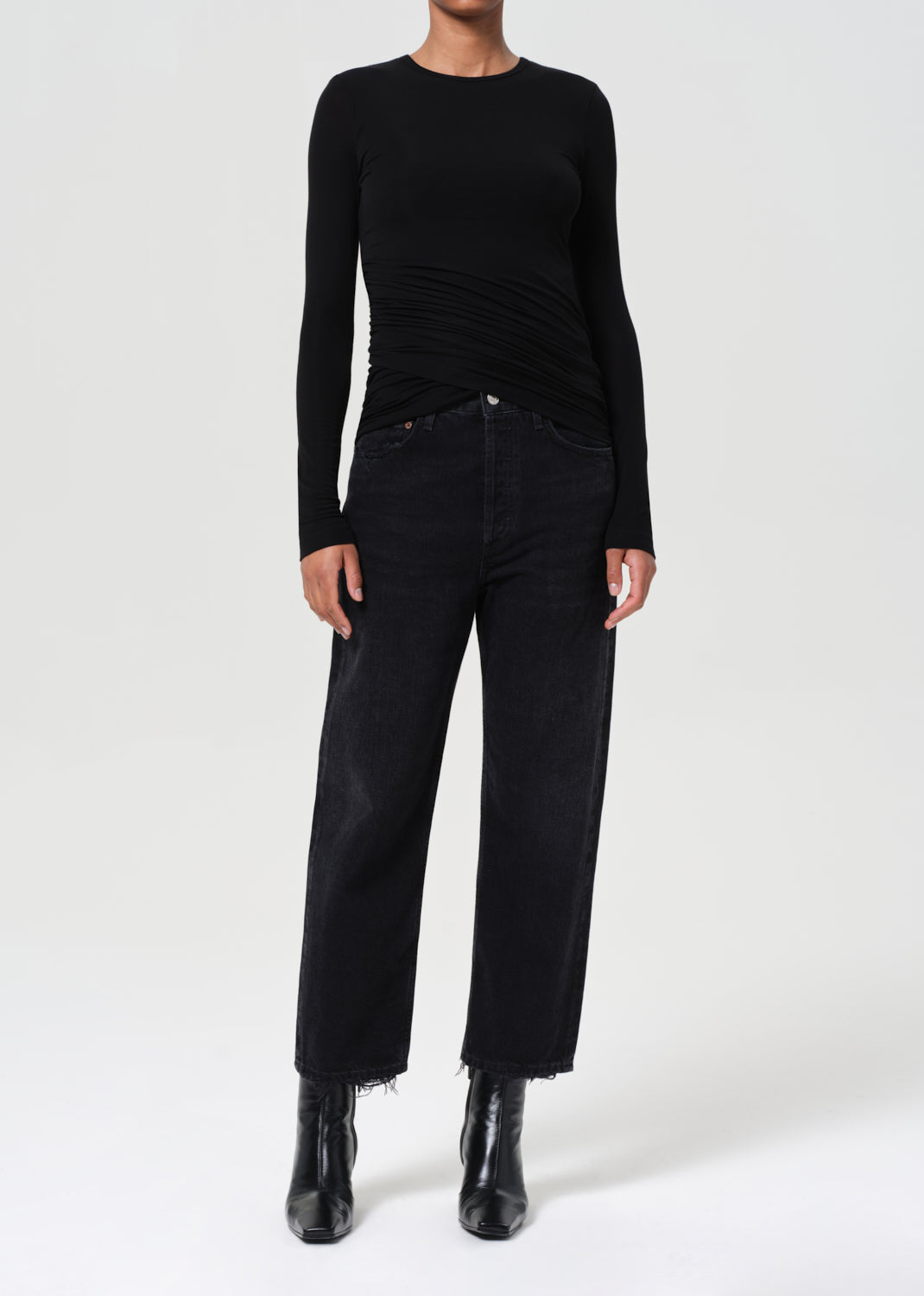 Person wearing a black long-sleeve top and black pants on a white background