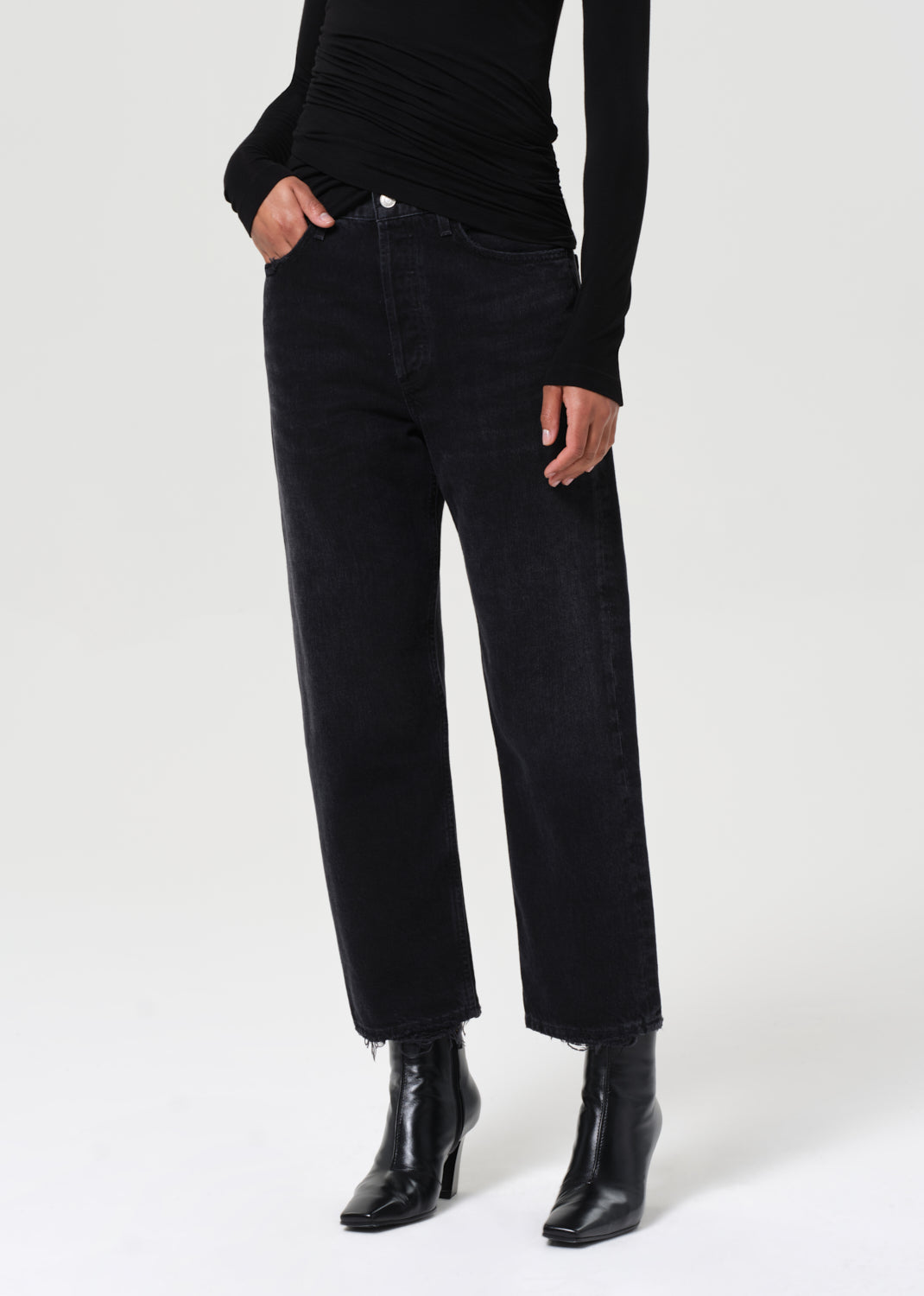 Person wearing black jeans and black boots on a white background