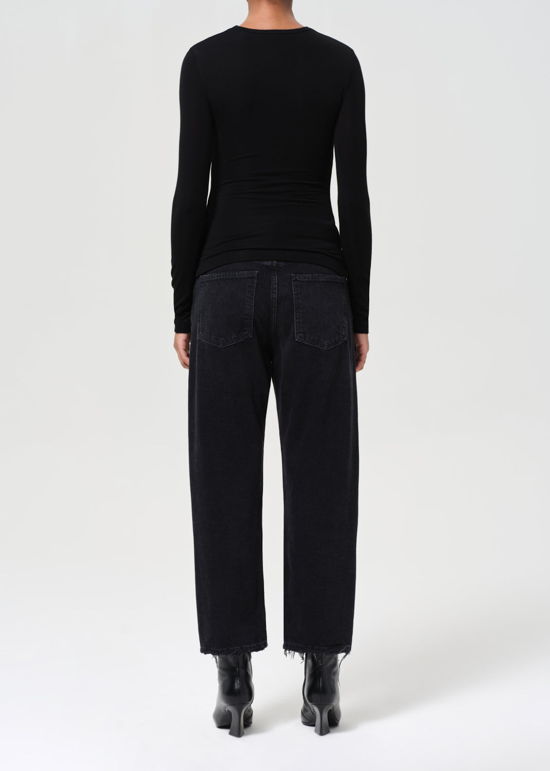 Person wearing a black long-sleeve top and black pants on a white background