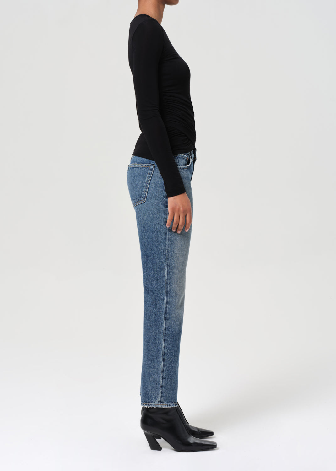 Person wearing blue jeans and a black top on a white background