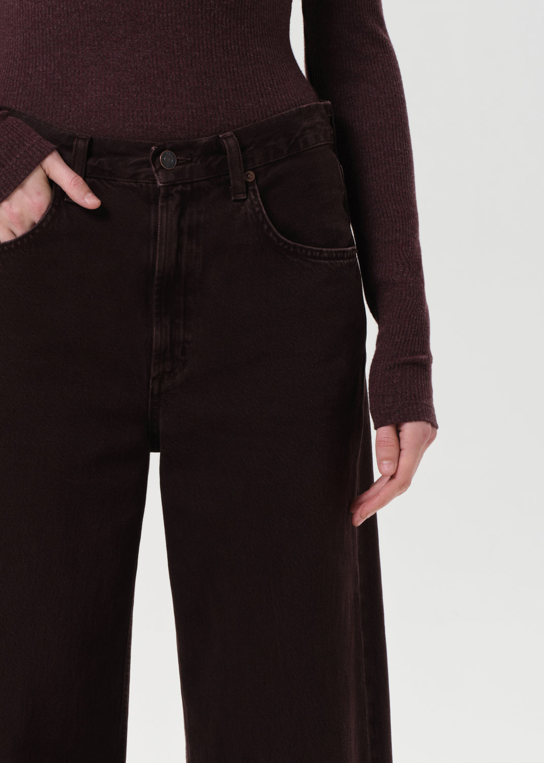 Person wearing dark brown pants and sweater on a white background