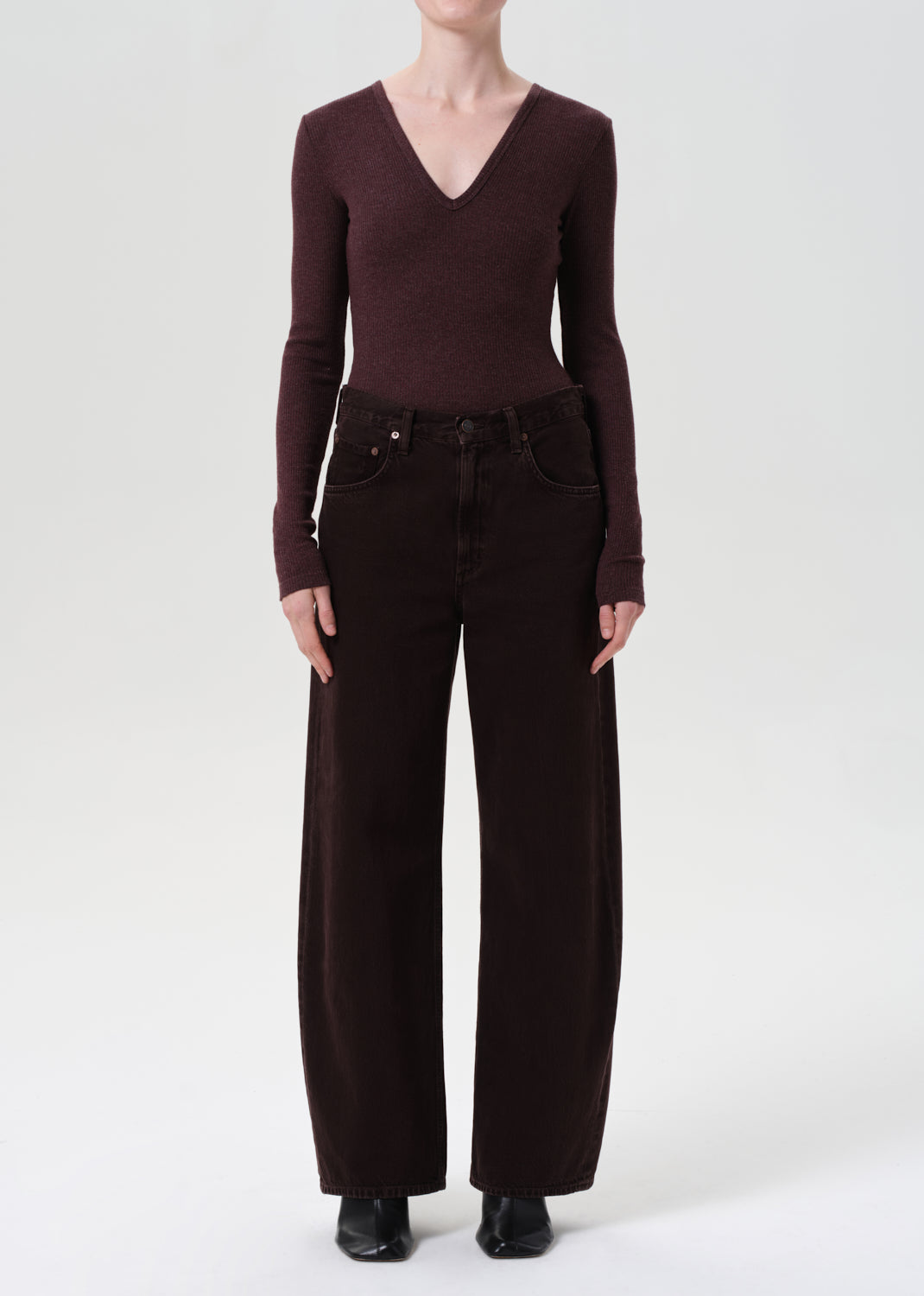 Person wearing a brown long-sleeve top and wide-leg pants on a white background