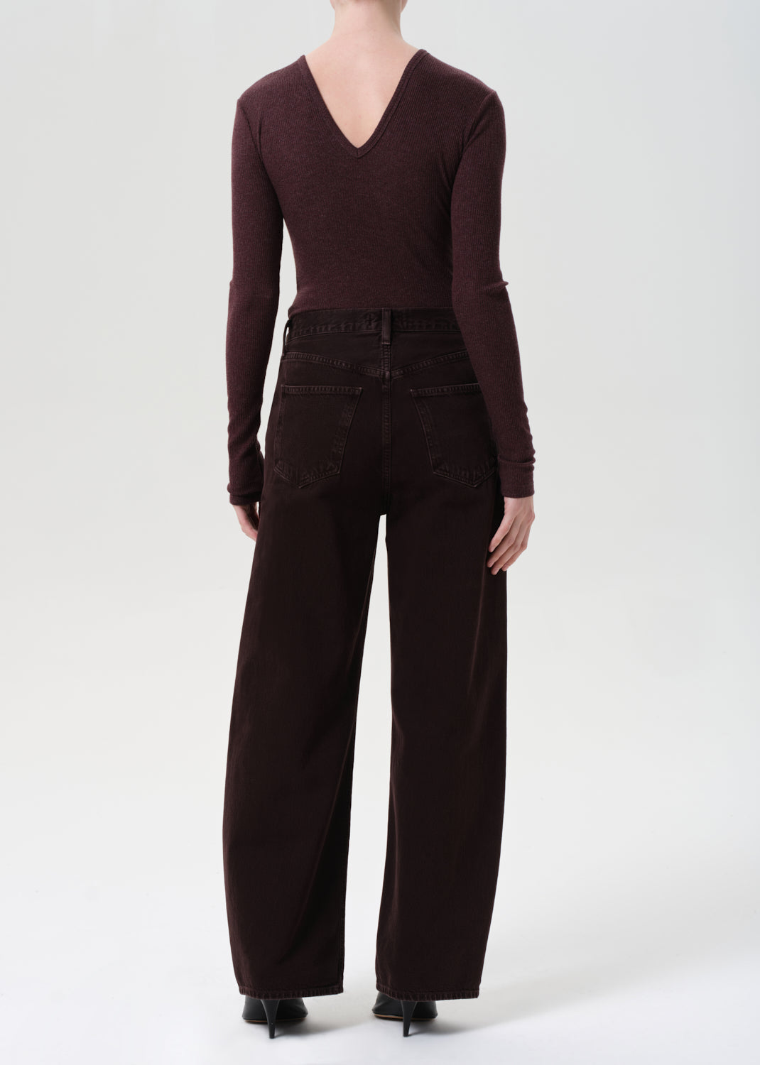 Person wearing a brown long-sleeve top and wide-leg pants on a white background