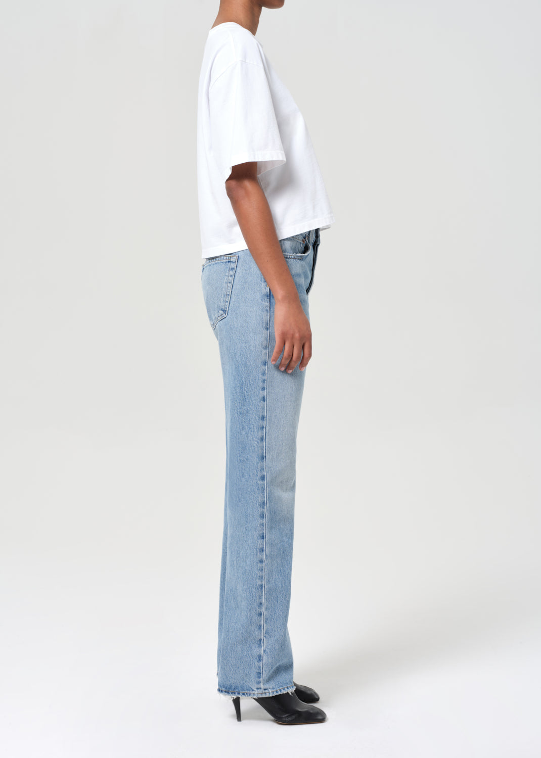 Person wearing light blue jeans and a white t-shirt on a plain background