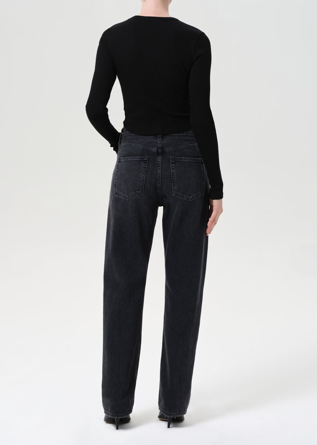 Person wearing black jeans and a black top on a white background