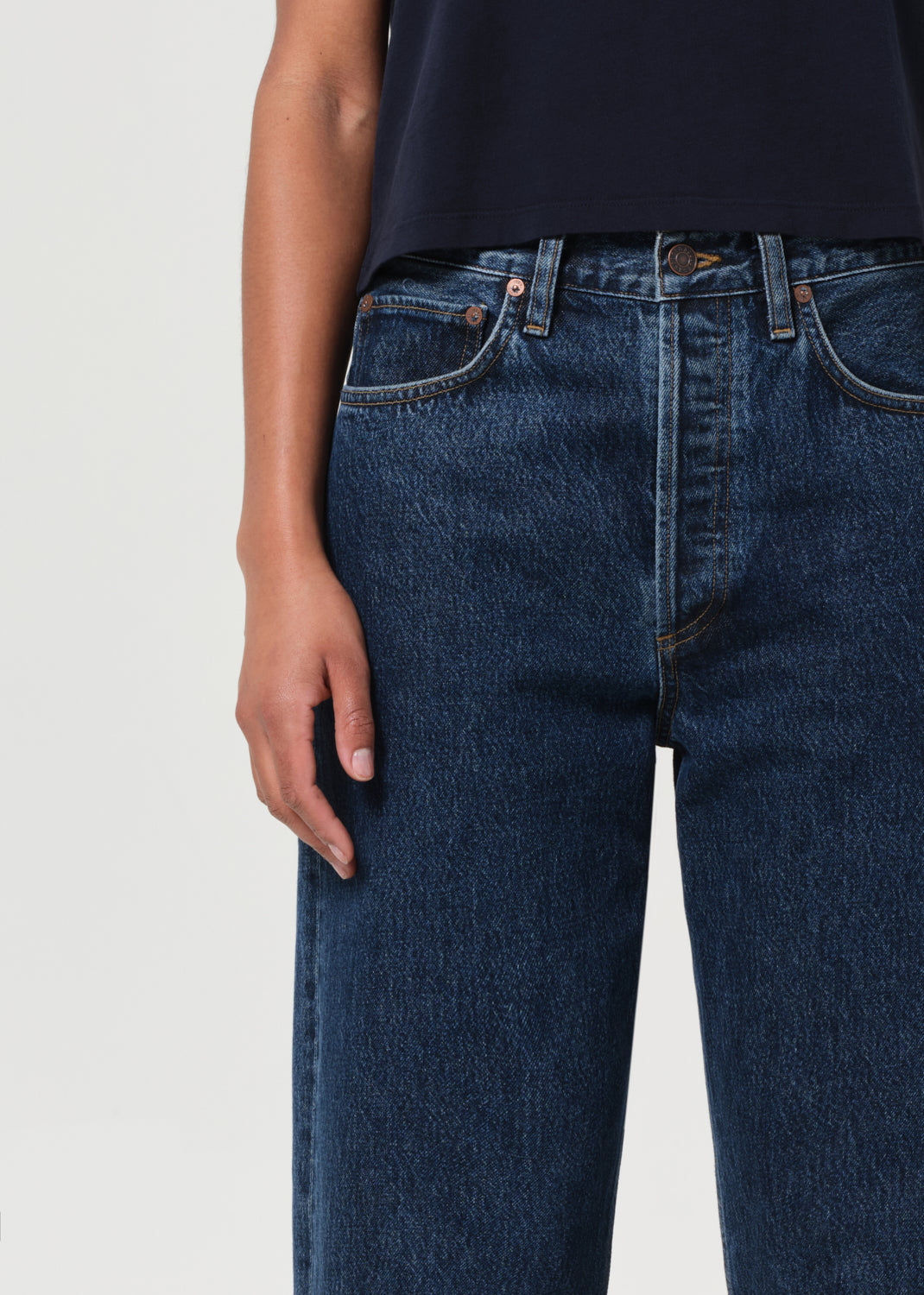 Person wearing dark blue jeans on a light gray background