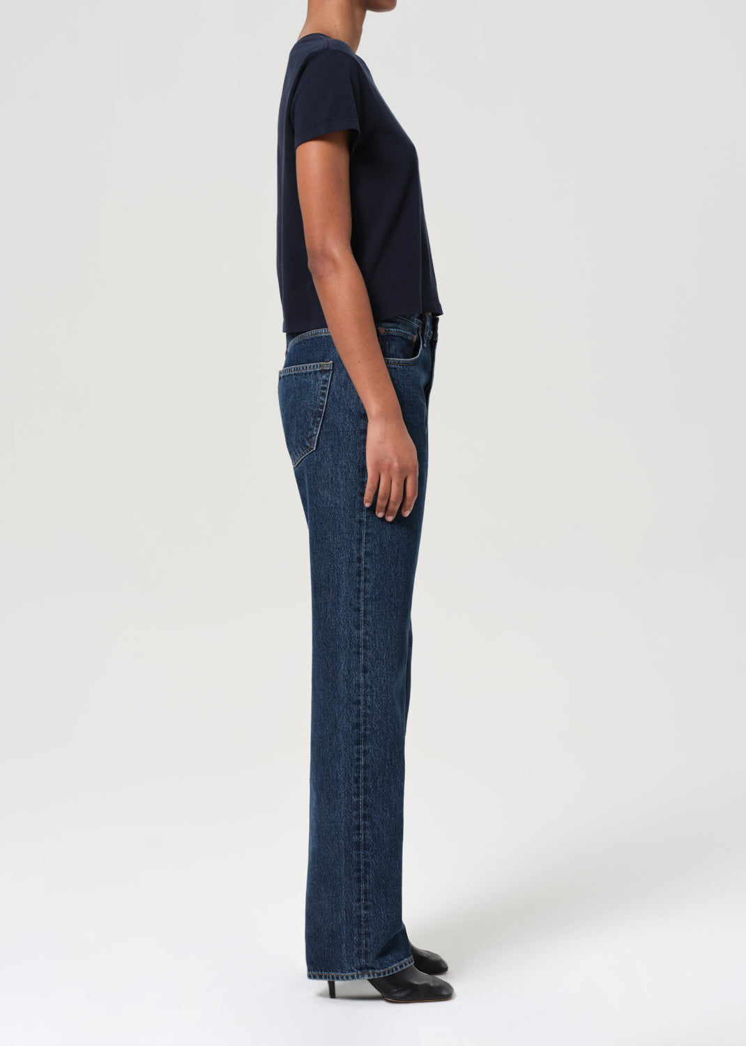 Person wearing a navy t-shirt and blue jeans on a white background
