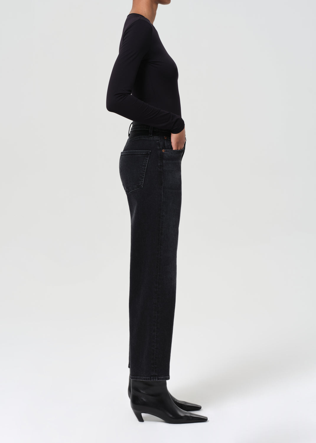 Person wearing black jeans and a black top on a white background
