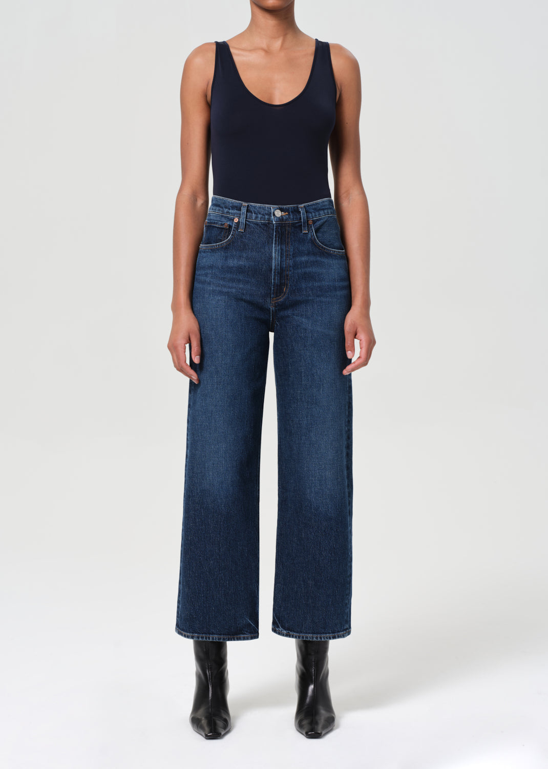 Person wearing dark blue jeans and a black tank top on a white background