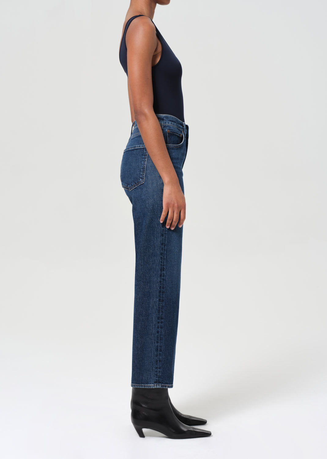 Person wearing blue jeans and black boots on a white background