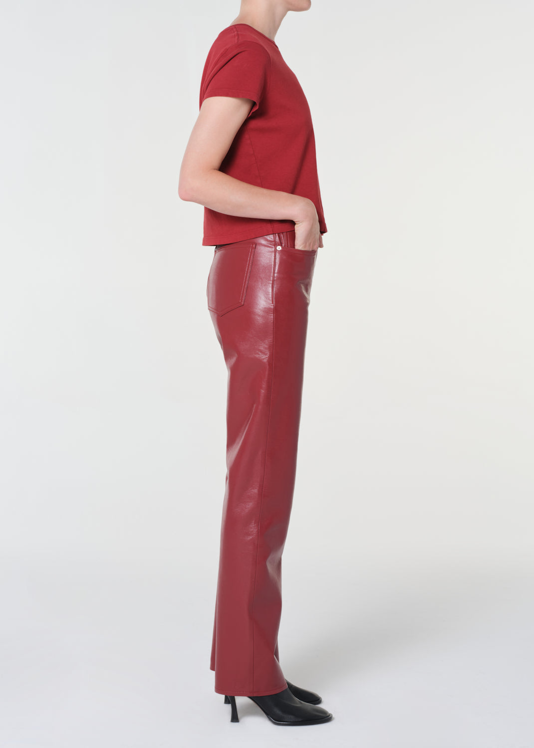 Person wearing a red top and red leather pants on a white background