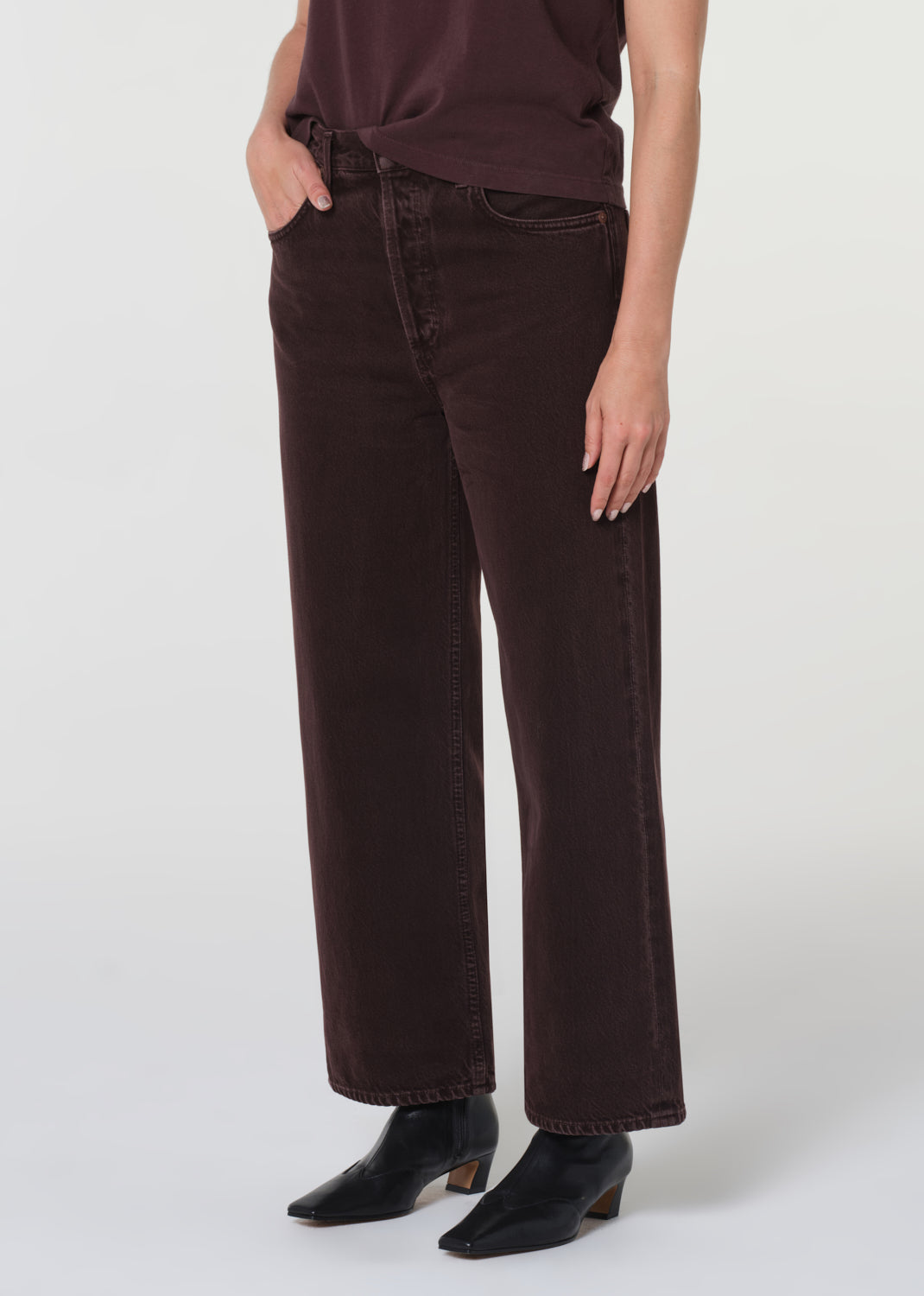 Person wearing dark brown wide-leg jeans on a white background