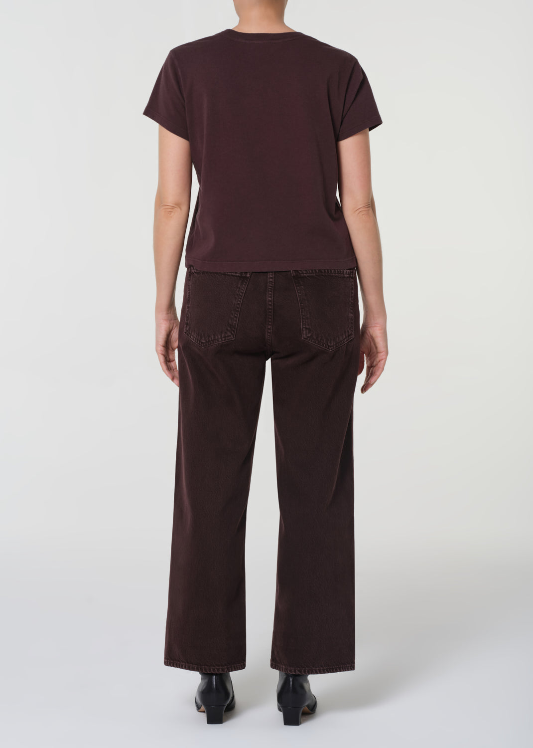 Person wearing a brown t-shirt and pants on a white background