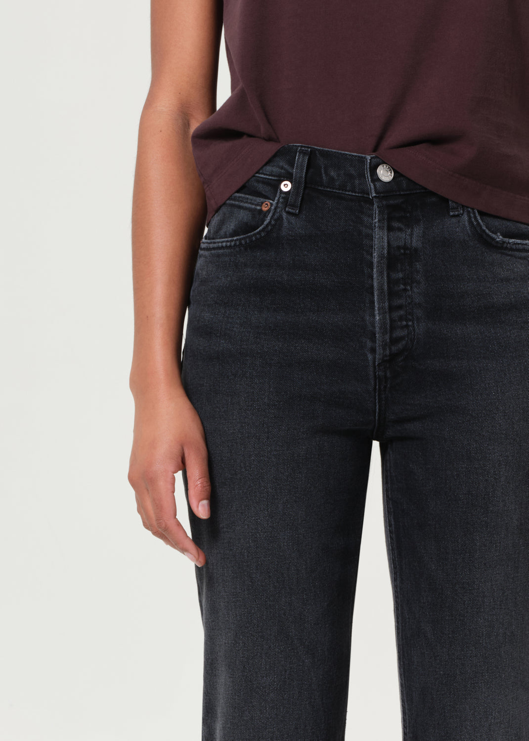 Person wearing black jeans and a maroon top on a light gray background