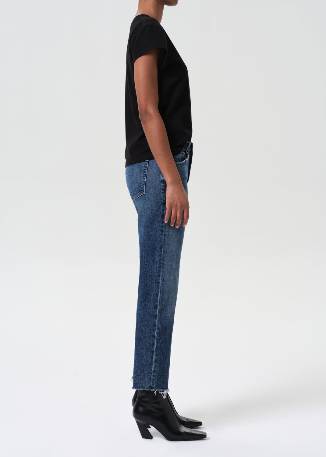 Person wearing a black top and blue jeans on a white background