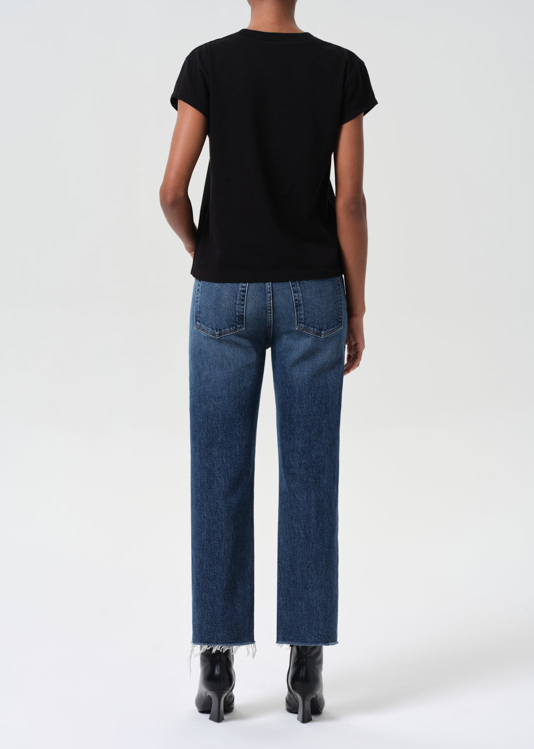 Person wearing a black t-shirt and blue jeans on a white background