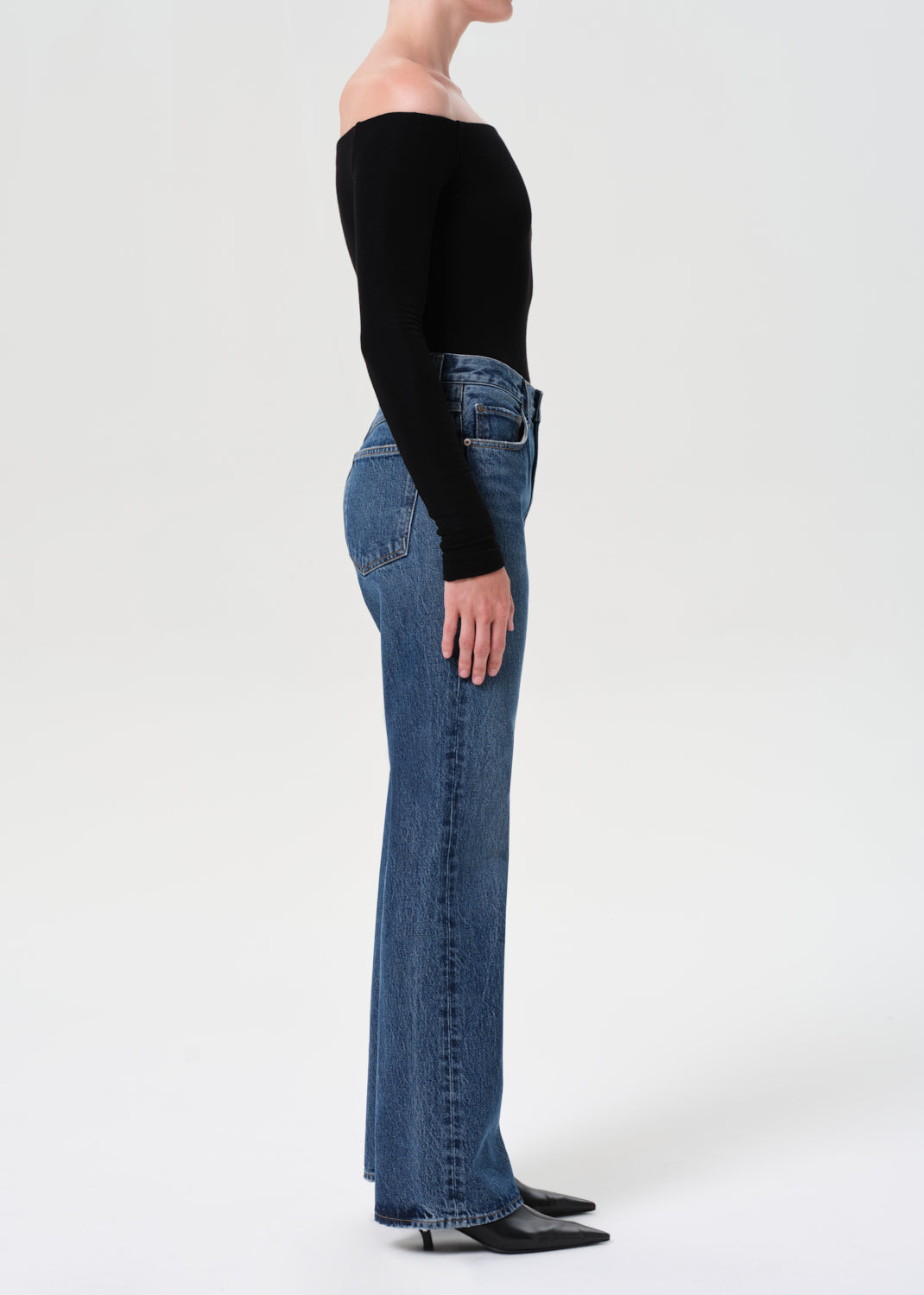Person wearing blue jeans and a black top on a white background