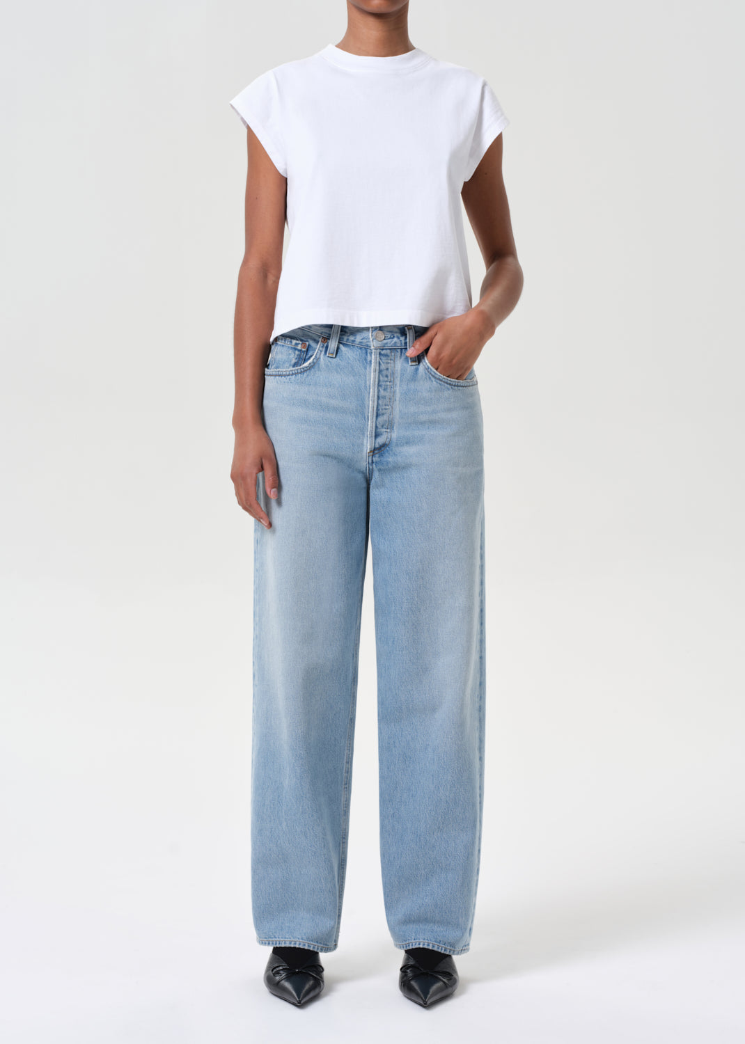 Person wearing light blue jeans and a white t-shirt on a white background