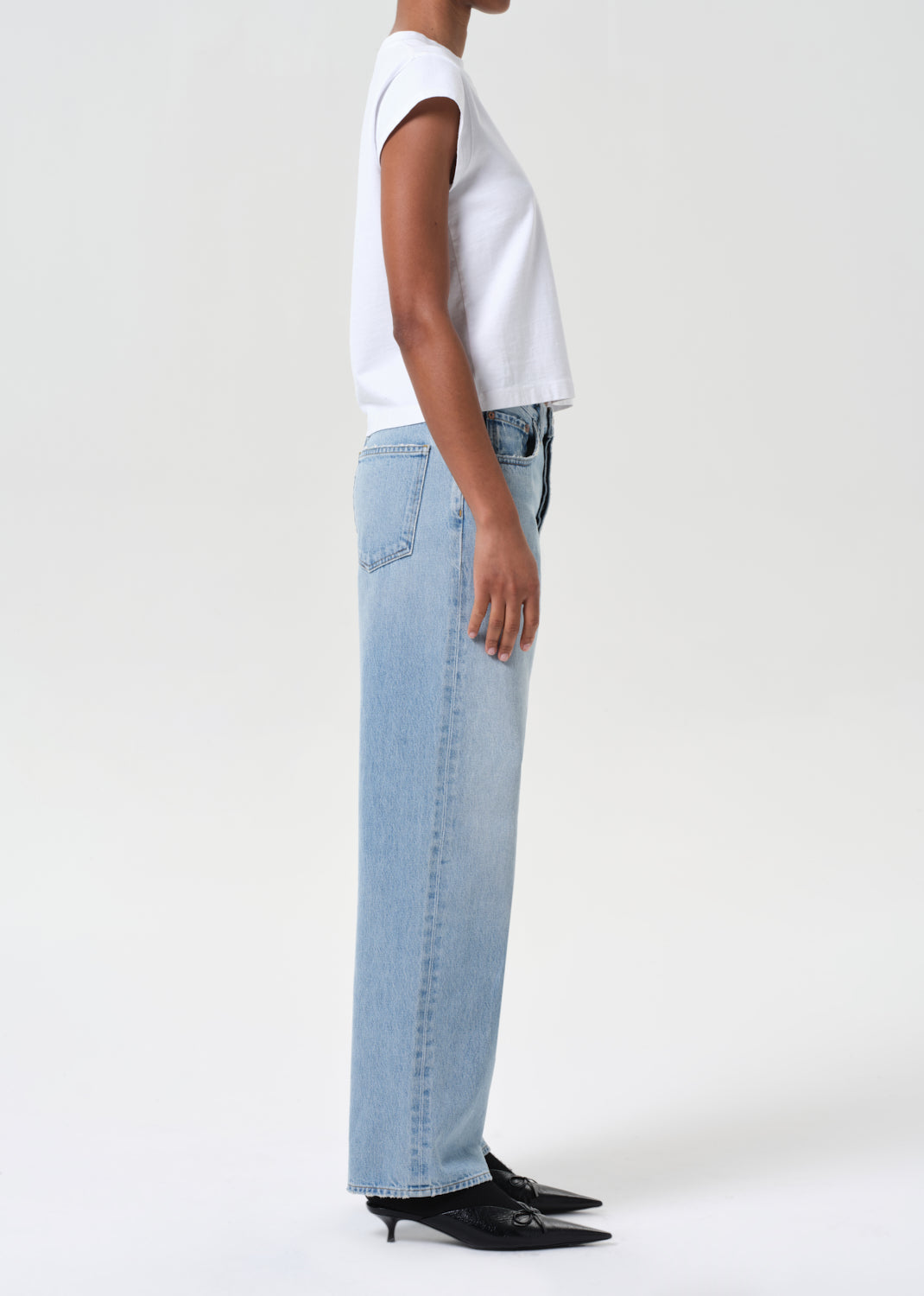 Person wearing a white top and light blue jeans on a white background