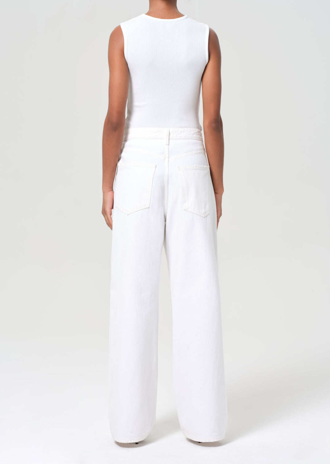 Person wearing a white sleeveless top and wide-leg pants on a white background