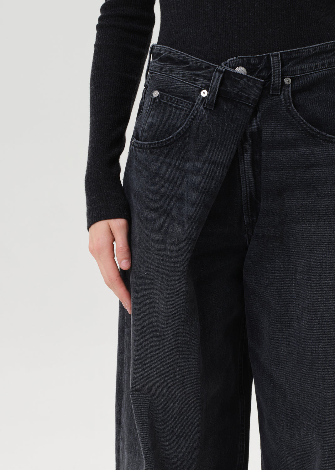 Person wearing black jeans on a light gray background