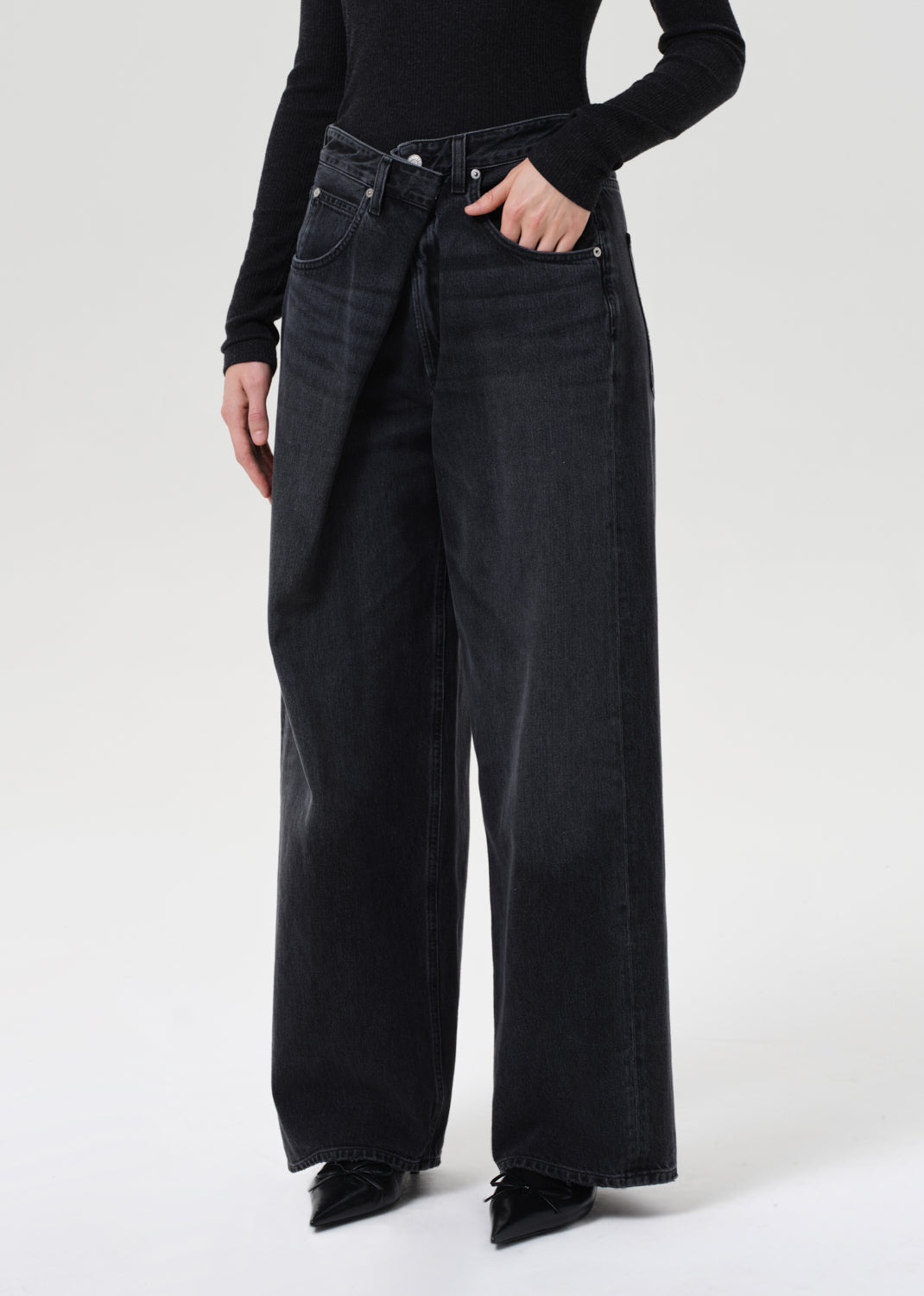 Person wearing black wide-leg jeans on a white background