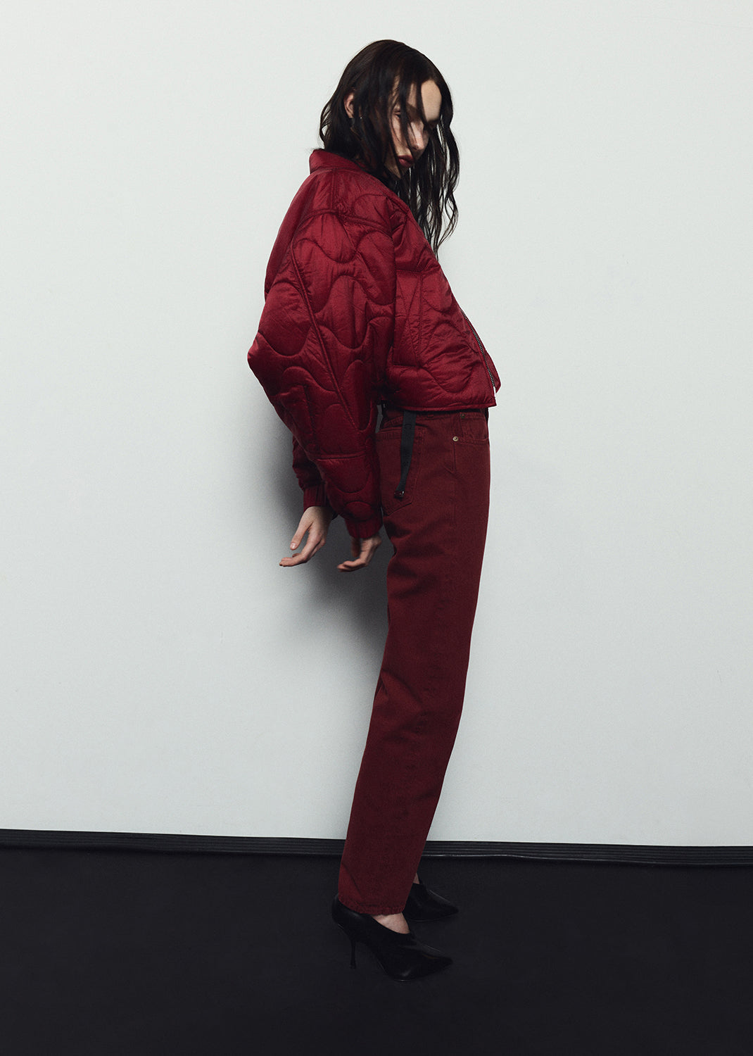 Person wearing a red puffer jacket and pants against a white background
