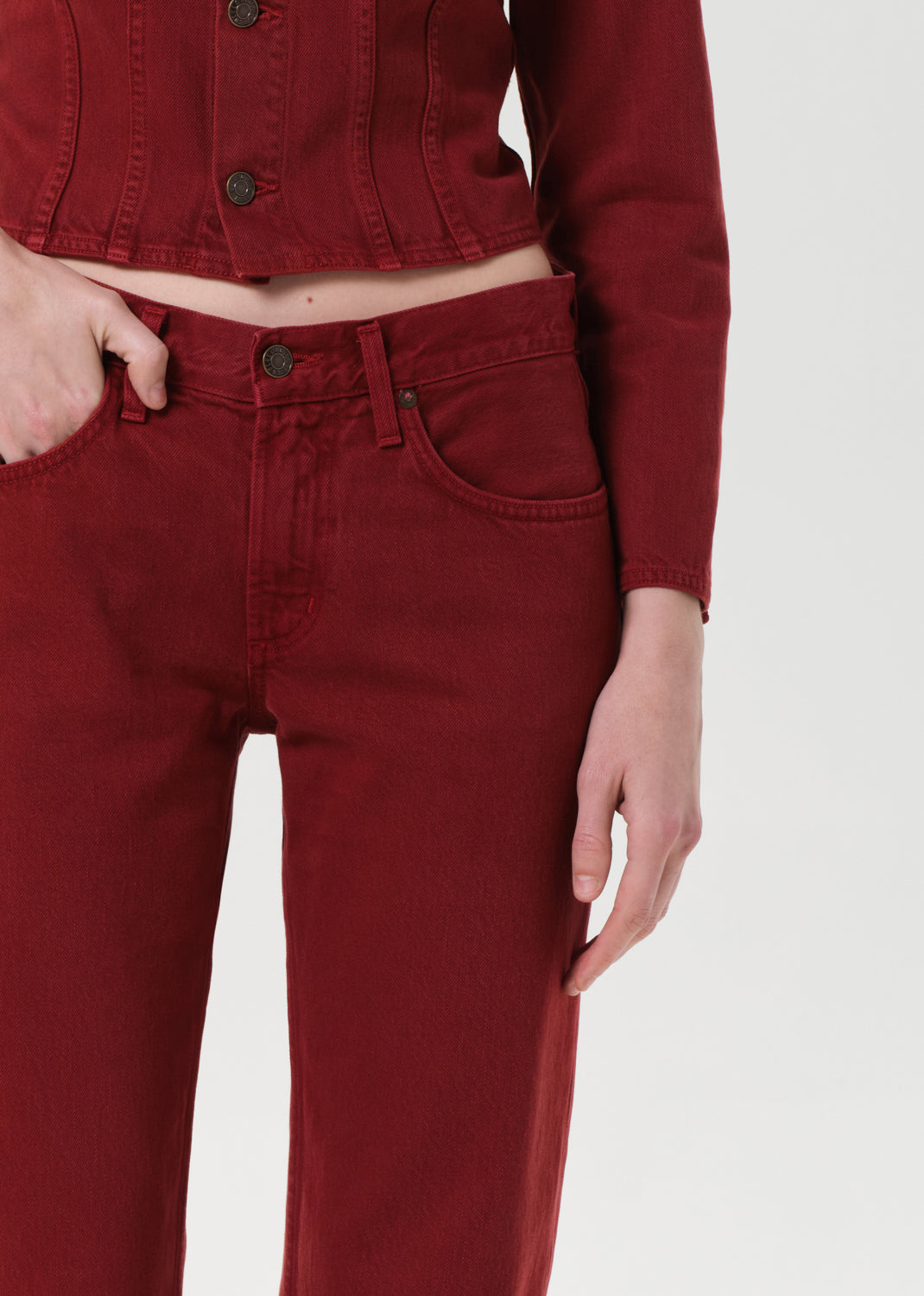 Person wearing a red cropped jacket and pants on a white background