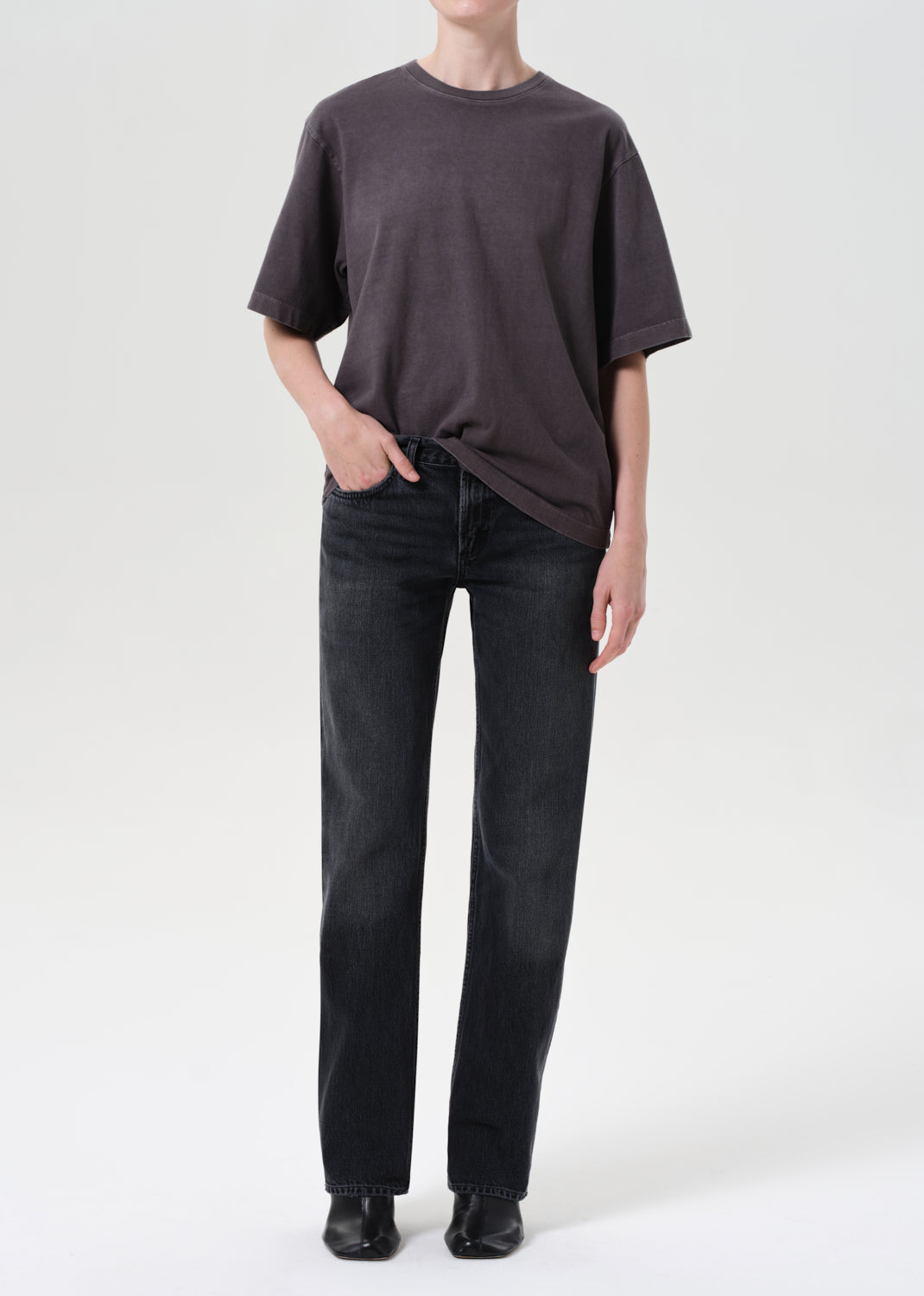 Person wearing a dark gray t-shirt and black jeans on a white background