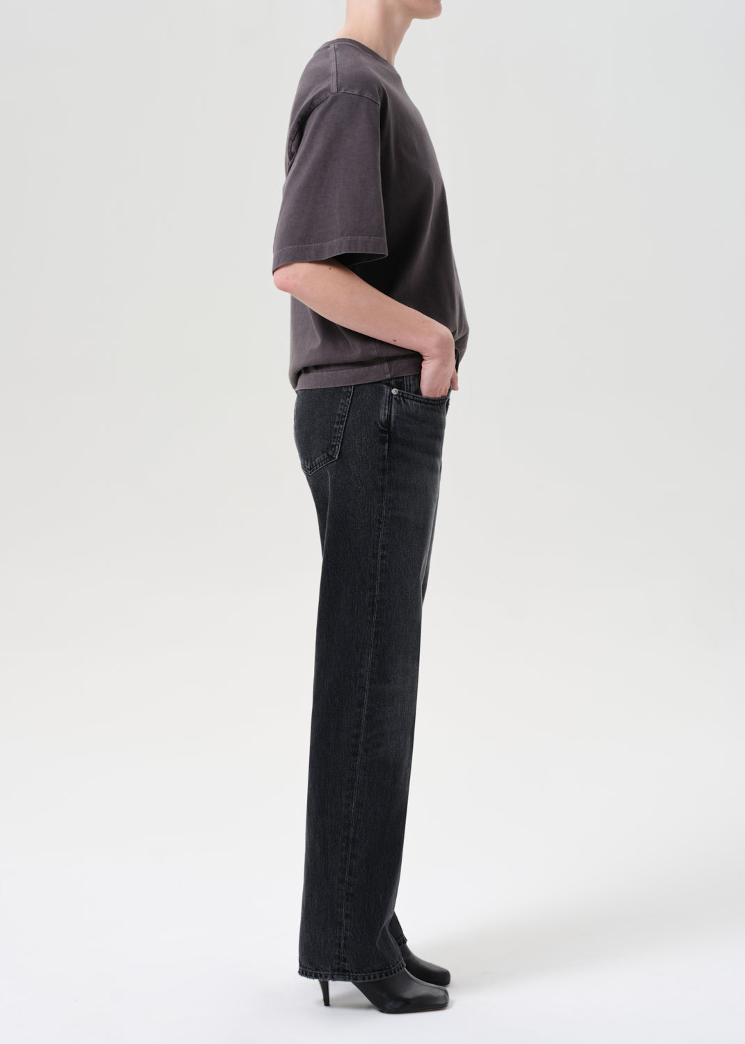 Person wearing a dark gray t-shirt and black jeans on a white background