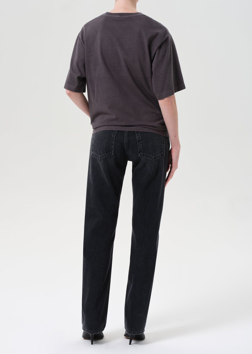 Person wearing a dark gray t-shirt and black jeans on a white background