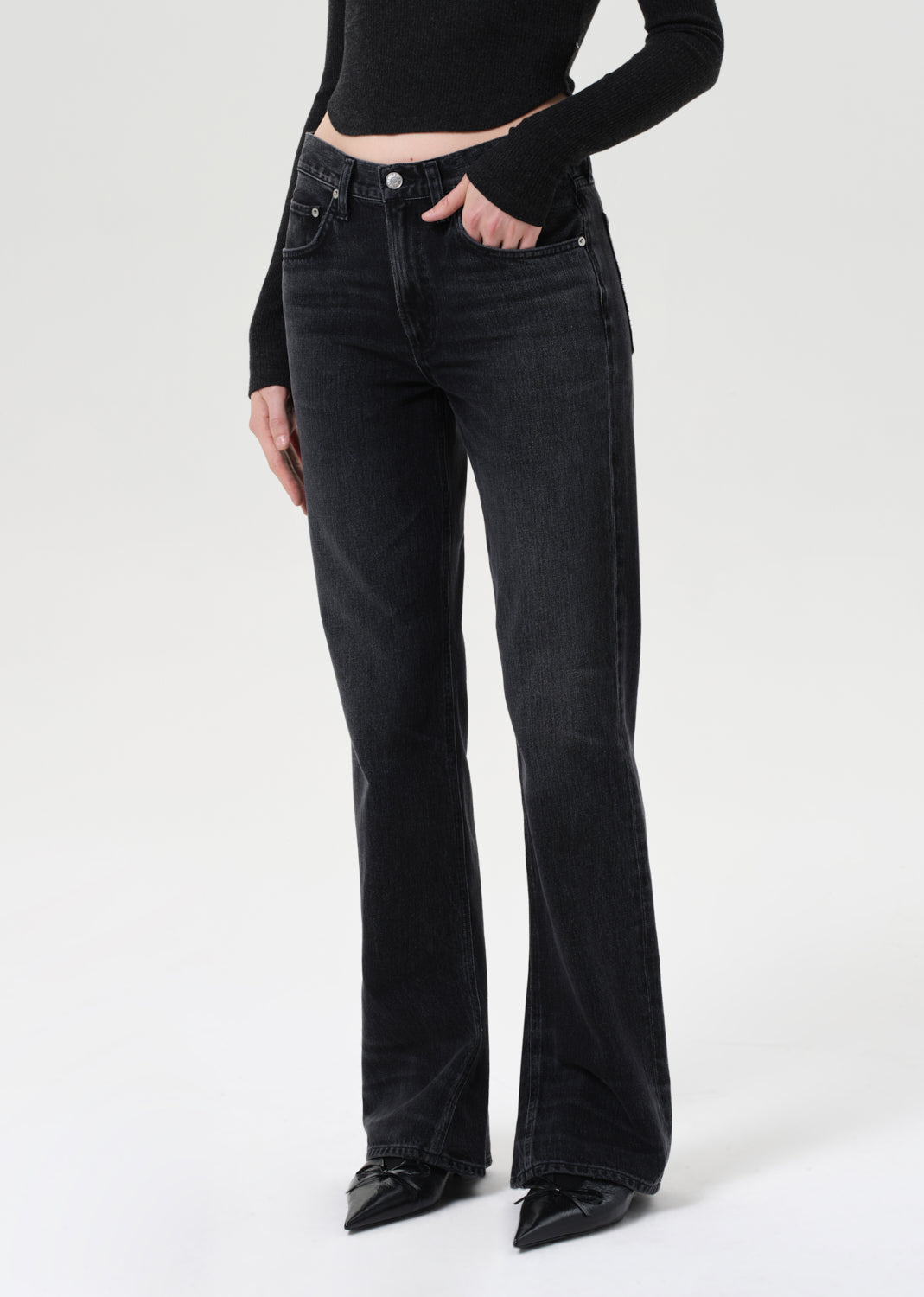 Person wearing black flared jeans and a black top on a white background