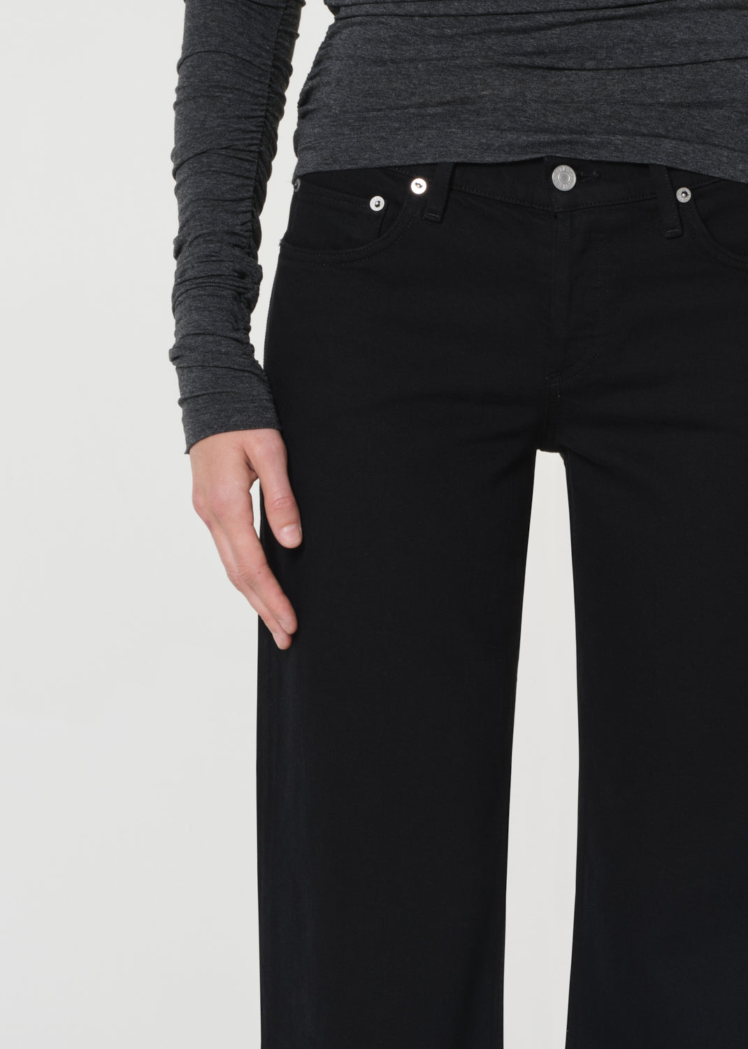 Person wearing black pants with a plain background