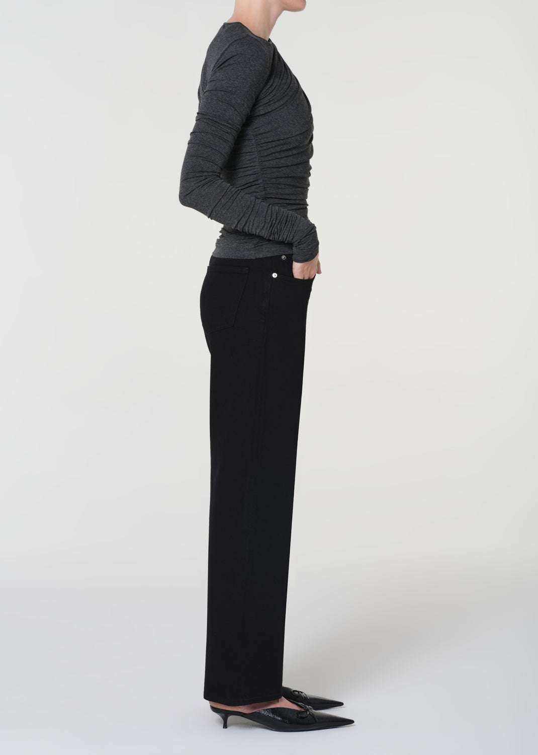 Person wearing a gray sweater and black pants on a white background