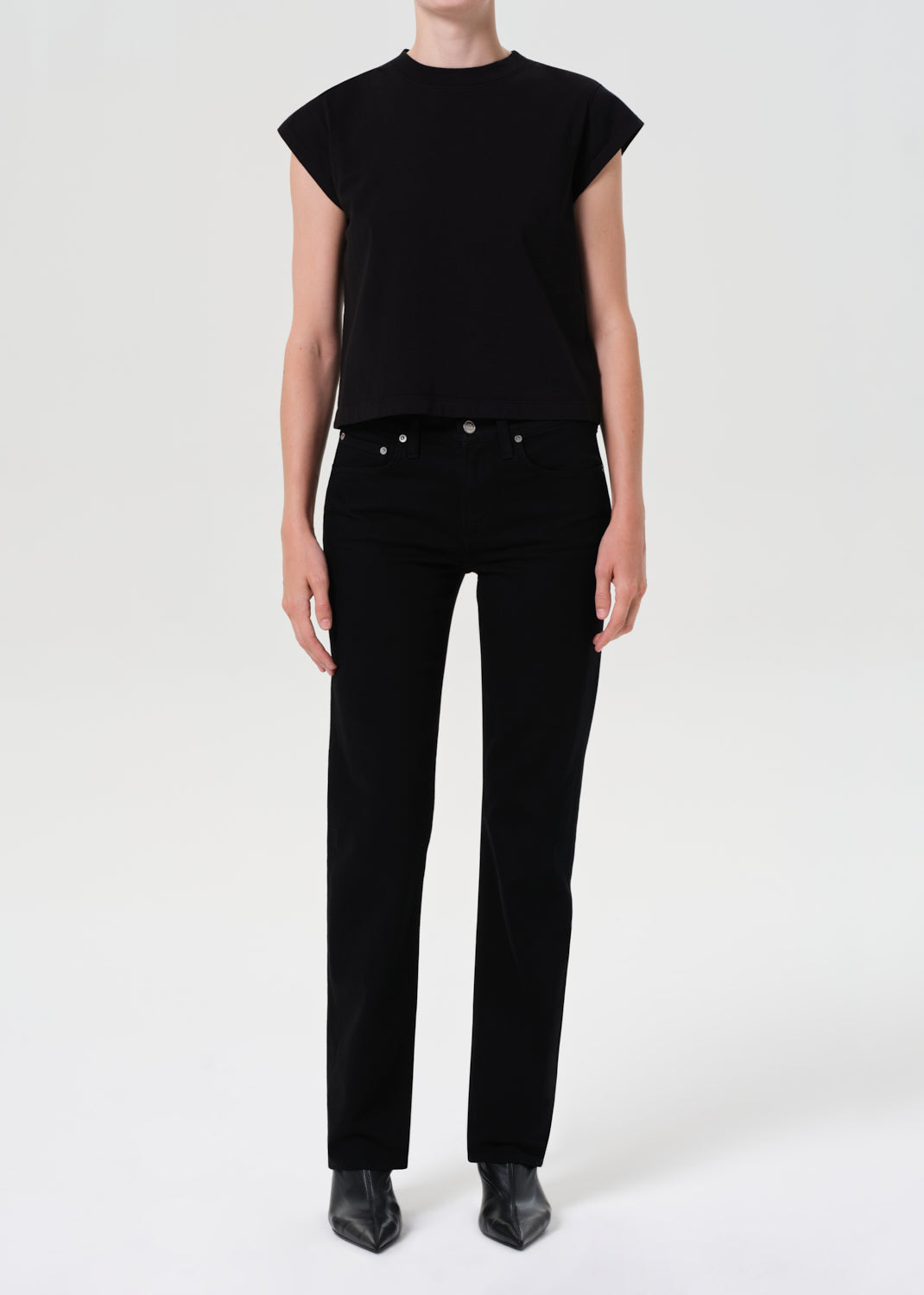 Person wearing a black sleeveless top and black pants on a white background