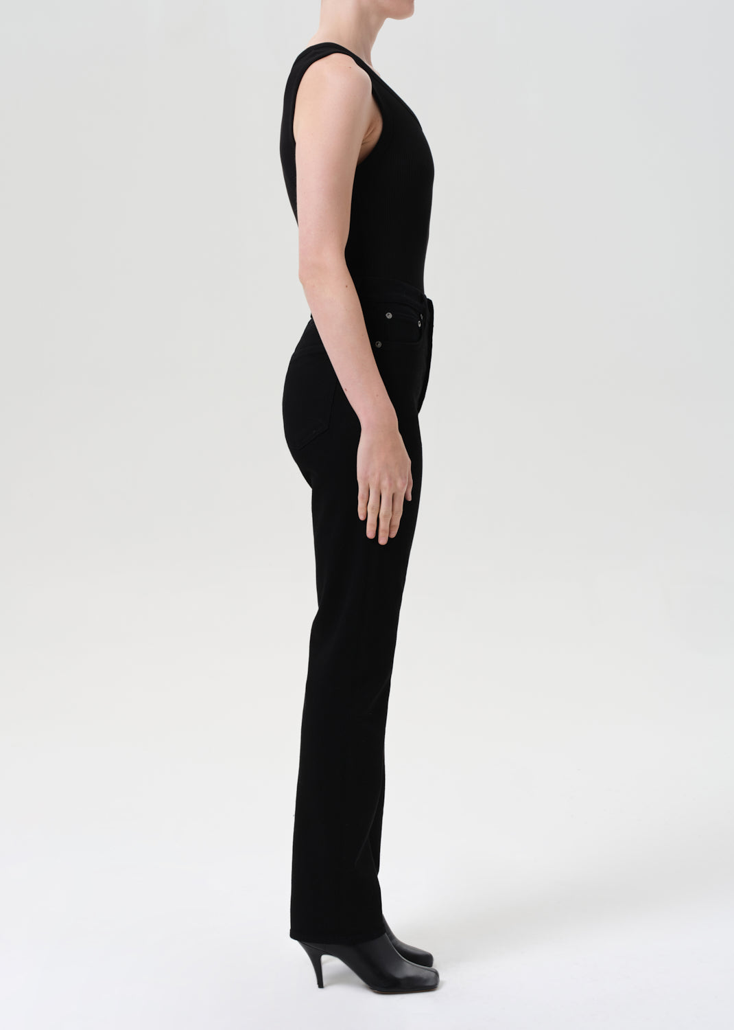 Person wearing a black sleeveless jumpsuit on a white background