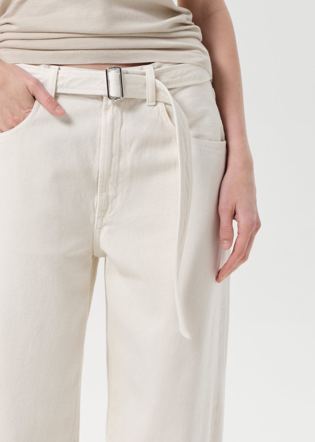 Beige pants with a belt worn by a person on a white background