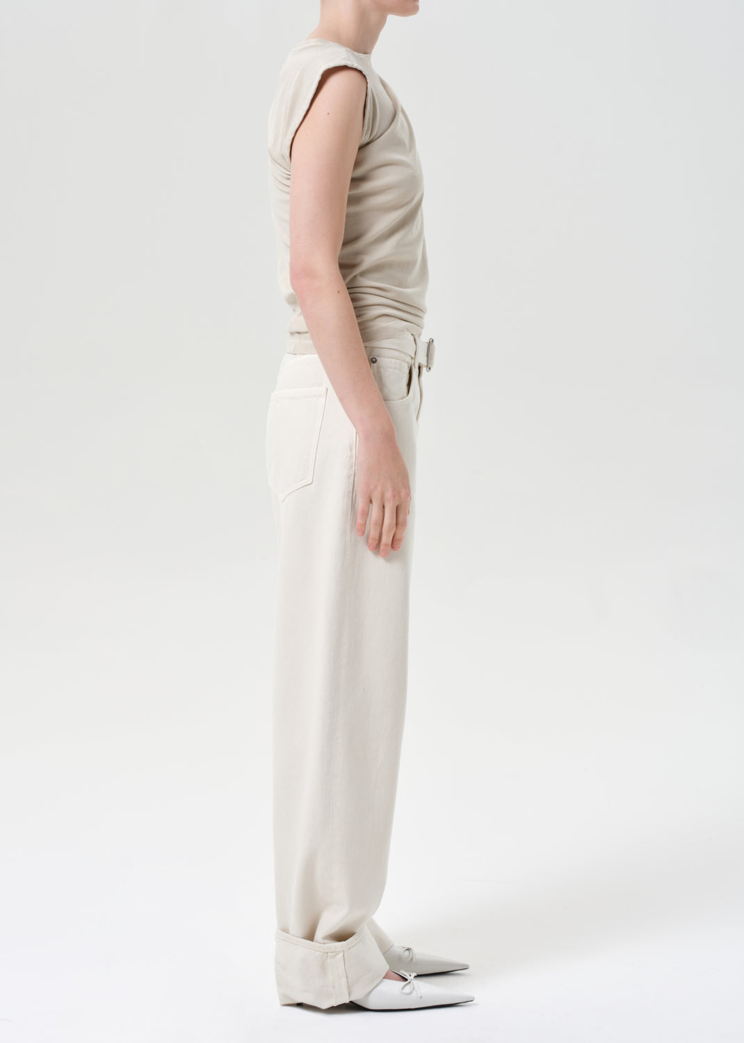 Person wearing a beige sleeveless top and wide-leg pants on a white background