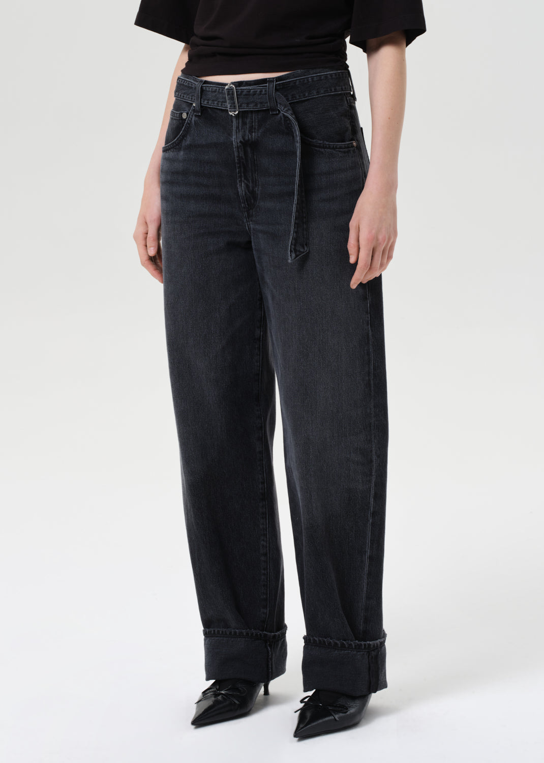 Person wearing black high-waisted jeans on a white background