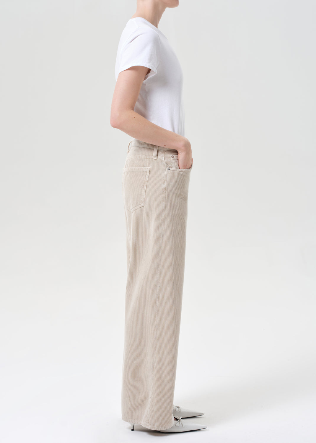 Person wearing a white t-shirt and beige pants on a plain background