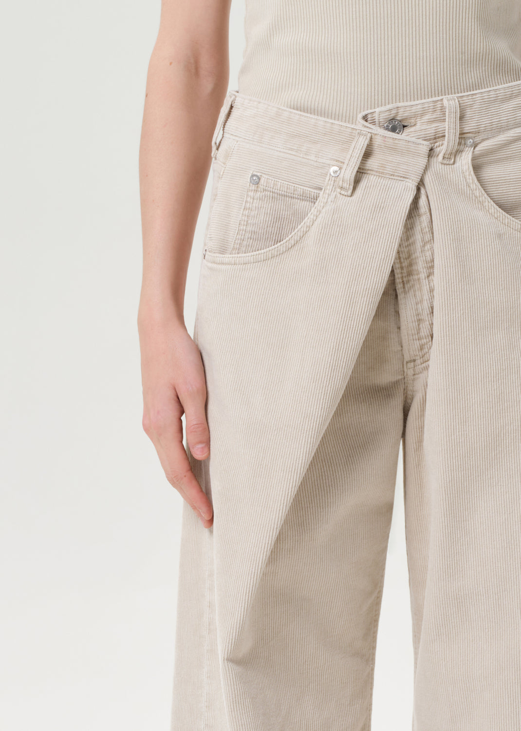 Beige corduroy pants worn by a person on a light gray background
