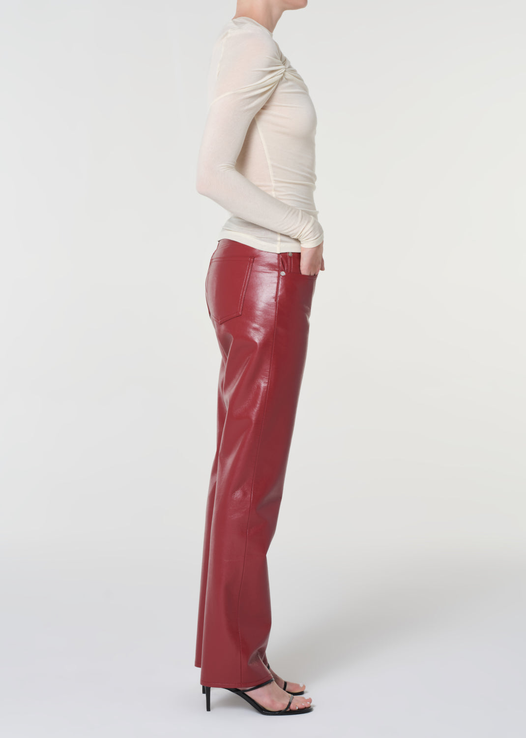 Person wearing red pants and a beige top on a white background