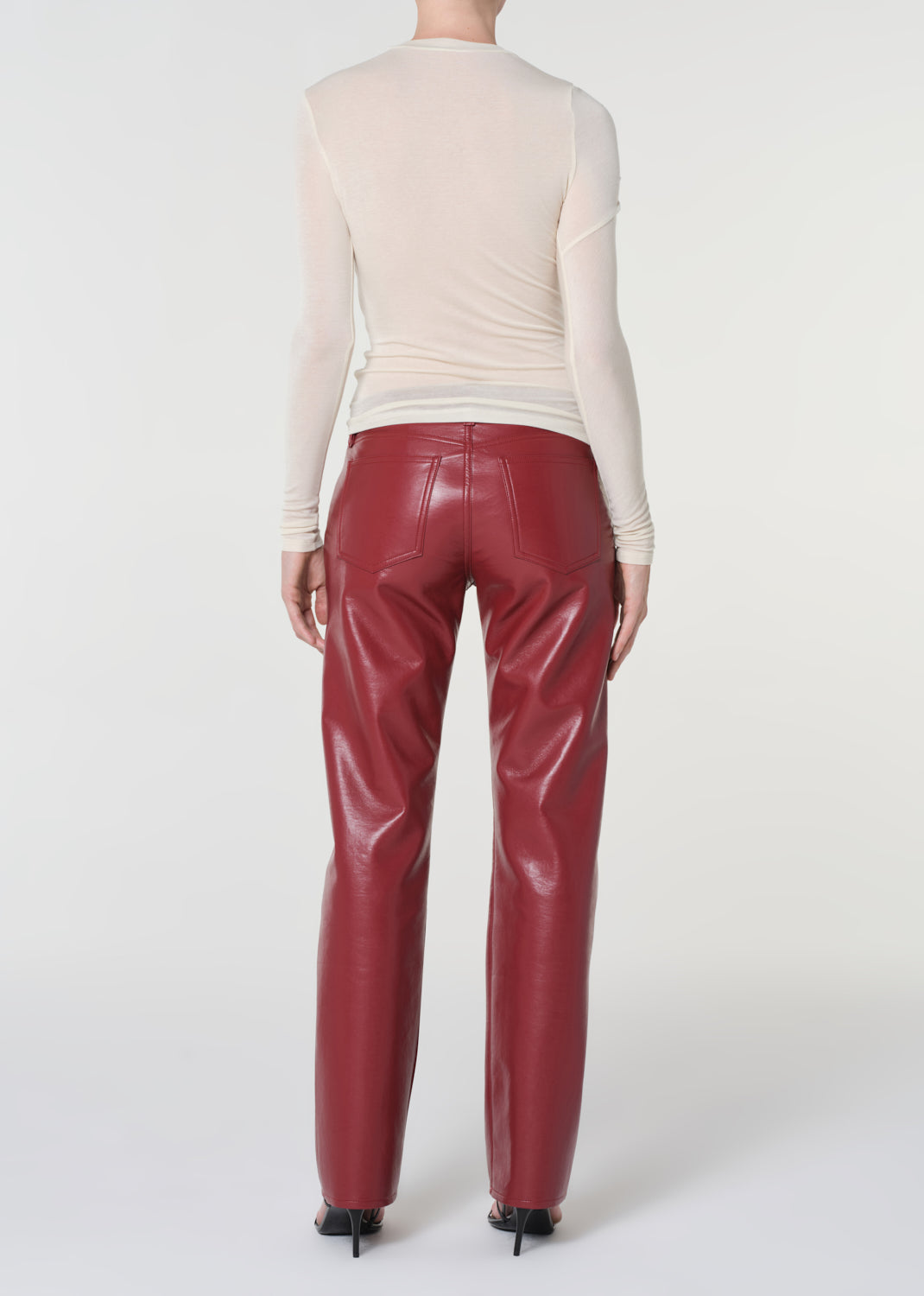 Person wearing a cream sweater and red pants on a white background